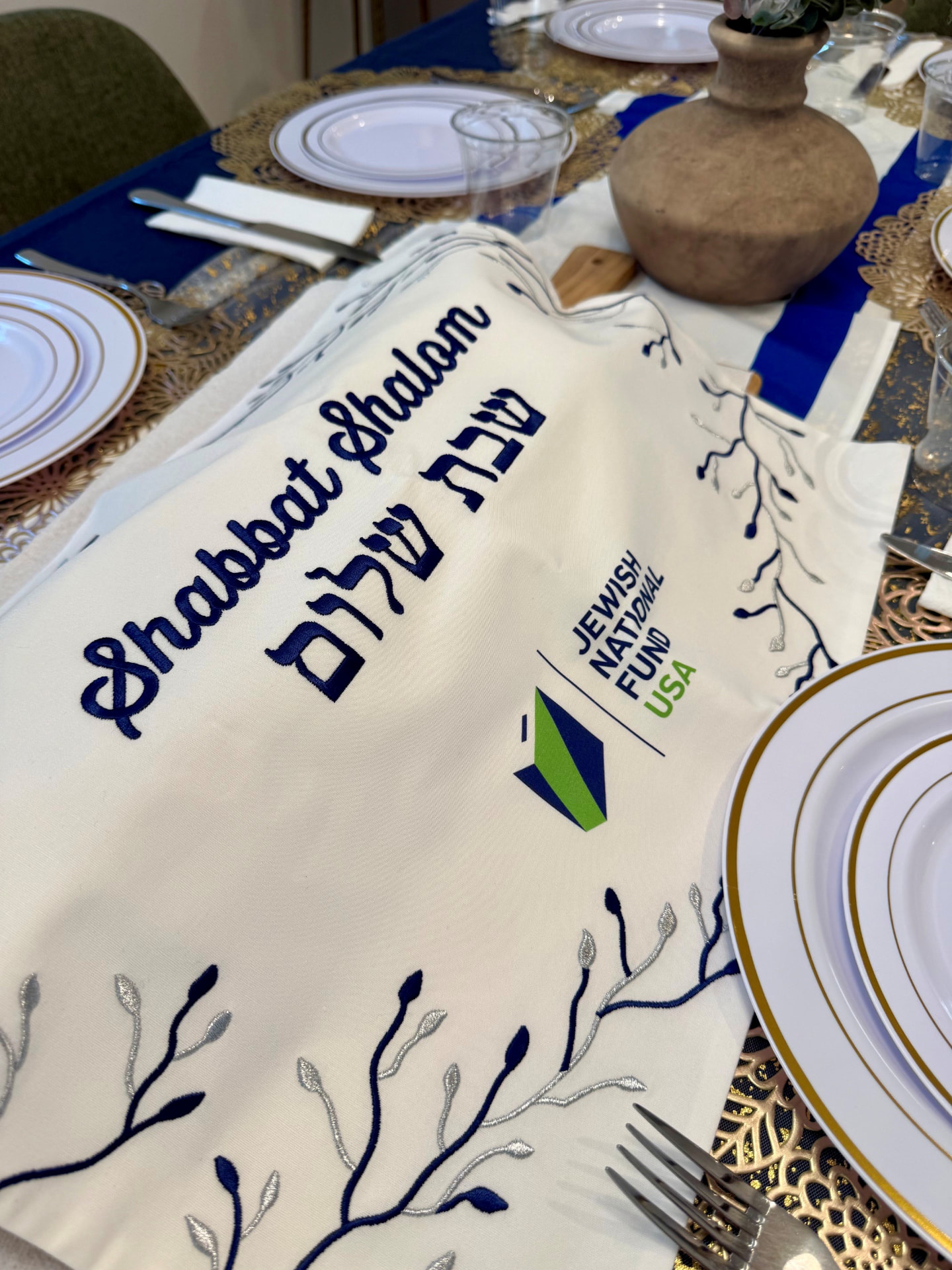 Young Jewish professionals in conversation at an elegant Shabbat dinner table with candles and challah
